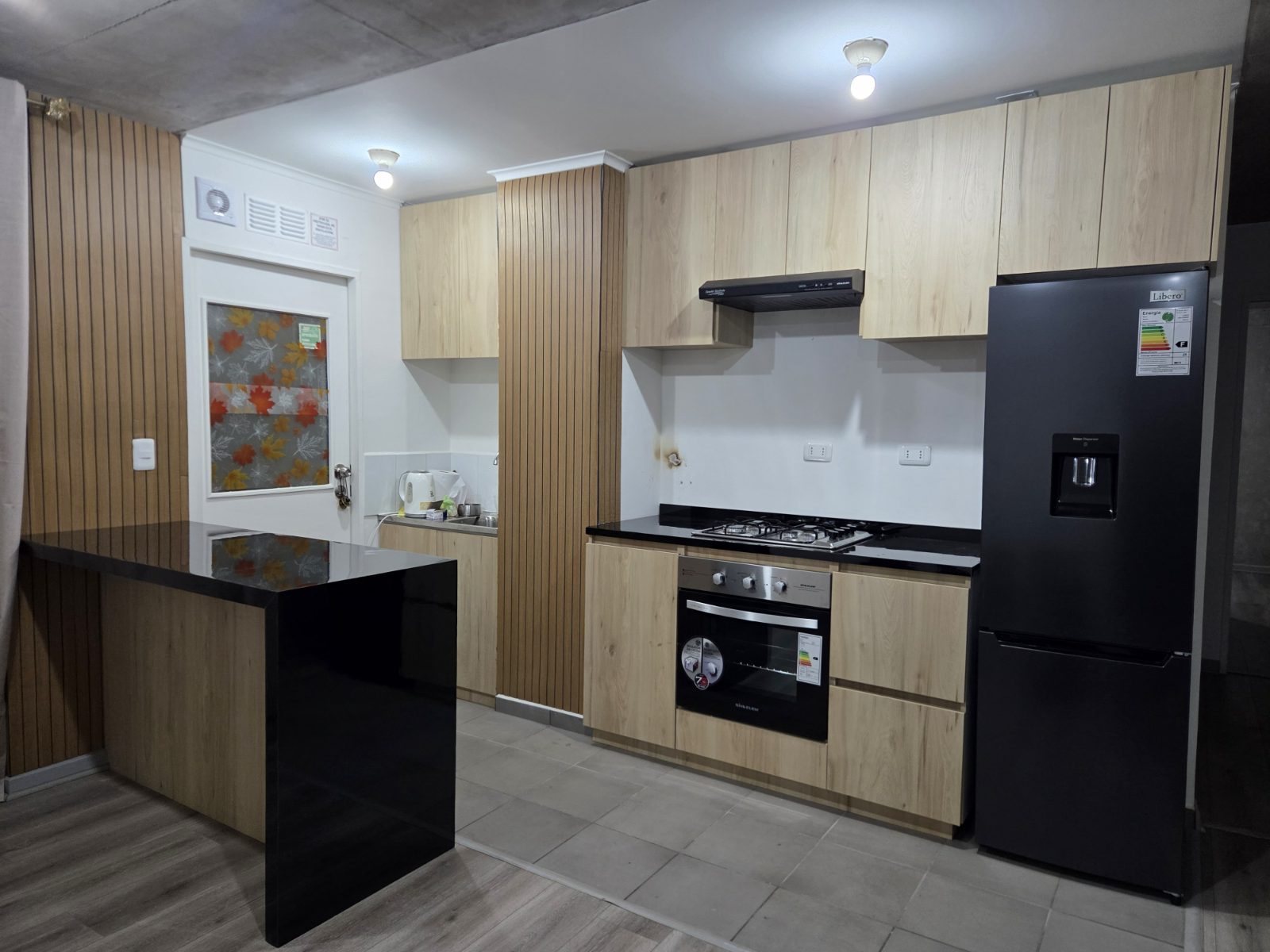 Cocina a medida con isla negra e instalación terminada en departamento de Colina